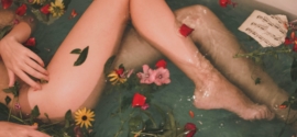 corpo femminile in una vasca da bagno con acqua e fiori