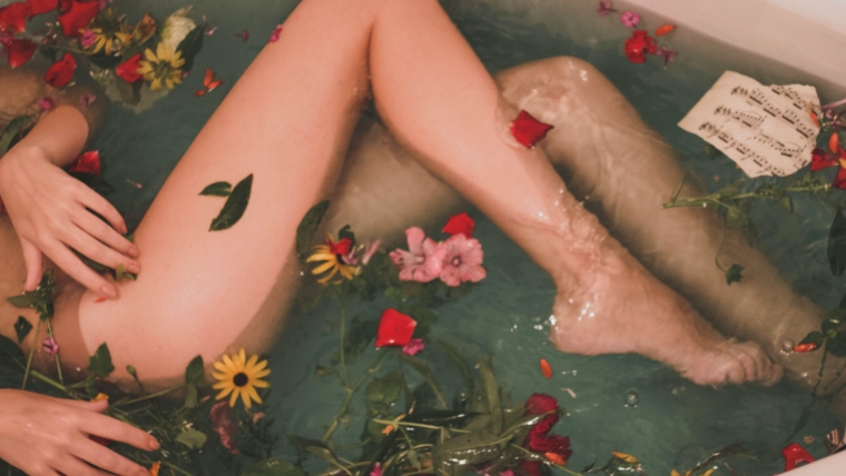 corpo femminile in una vasca da bagno con acqua e fiori